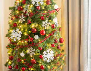 Warmly lit Nordic-style living room featuring a lush Christmas tree adorned with red ornaments,...
