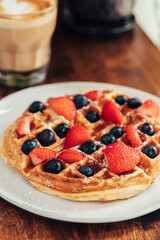 Waffle with Fresh Strawberries and Blueberries Beside Latte