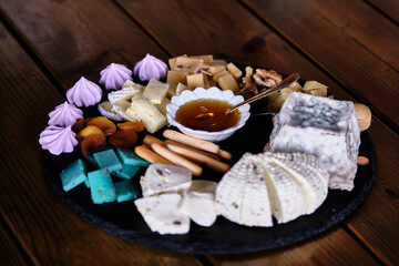Delicious assortment of cheeses and sweets on a rustic wooden table with honey