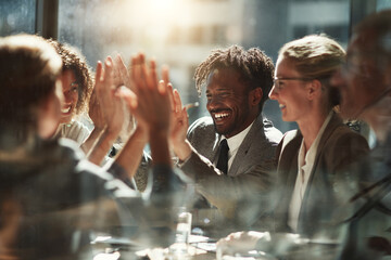 Smiling diverse business colleagues giving high fives in a bright office meeting success celebration