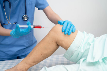 Doctor checking Asian elderly woman patient with scar knee replacement surgery in hospital.