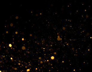 Elegant shimmering gold dust and glowing particles creating a magical bokeh effect on a black background.
