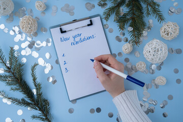 Female hands writing handwritten new year resolutions aims goals on paper notepad. Preparation for...