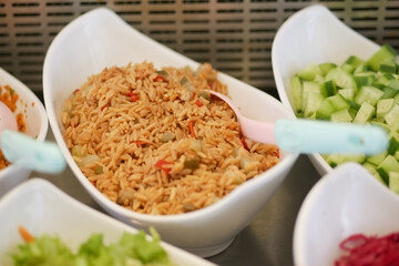 Savory rice dish served with fresh vegetables at a buffet
