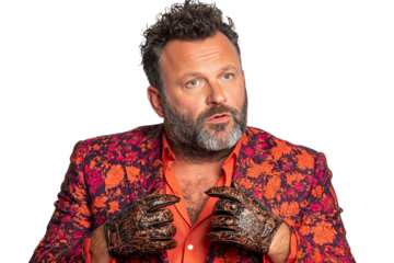 A man in a vibrant floral suit speaks expressively, showcasing unique style and creativity, emphasizing personal flair and individuality.