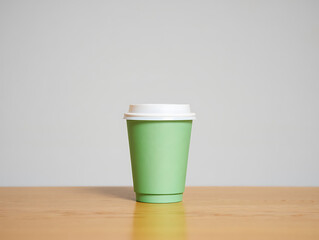A single green disposable coffee cup with a white lid sits on a wooden table