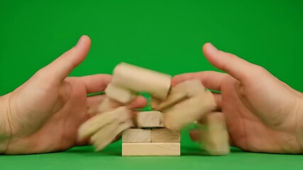 Hands Building and Toppling Wooden Block Tower on Green Screen - Close-up view of two hands carefully constructing a tower of wooden blocks against a bright green screen background. - Powered by Adobe
