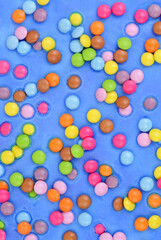 Blue icing with scattered sugar shell covered chocolate beans cake decoration background texture