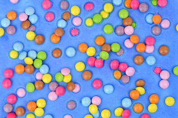 Blue icing with scattered sugar shell covered chocolate beans cake decoration background texture