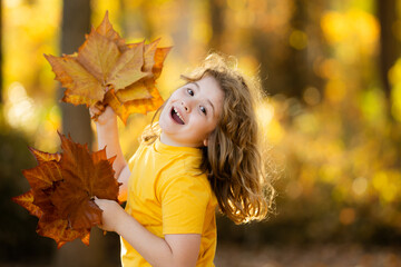 Kid with leaves in autumn park. Kid having fun outdoor. Enjoying autumn. Fall background. Portrait...