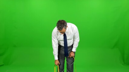 Tailor Measuring Invisible Client on Green Screen - A businessman, dressed in a white shirt and grey trousers, uses a tape measure to take measurements, seemingly of an invisible person.