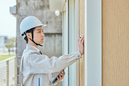 建物を確認する作業服姿の男性