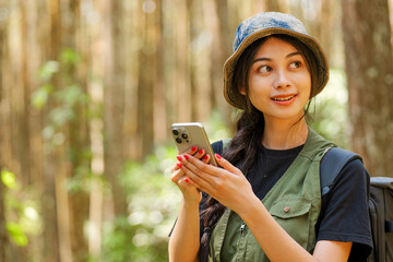 A woman wearing a green vest and a hat is holding a cell phone. She is pointing at the screen