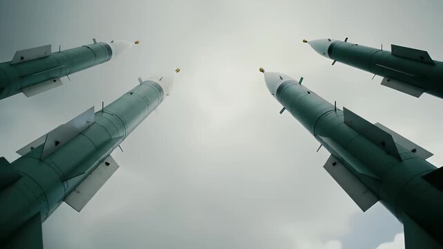 Looking Up at a Row of Metallic Green Missiles Against Cloudy Grey Sky