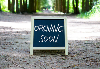 Opening soon symbol. Concept word Opening soon on chalk blackboard. Beautiful forest background....