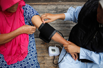 Female Health Worker Checks Blood Pressure of Elderly Woman in Rural Area During Medical Visit