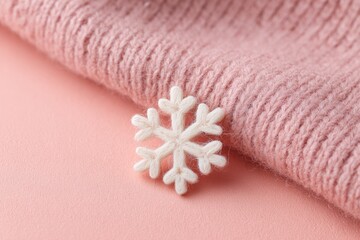 Delicate snowflake embellishment resting on soft pink knit fabri