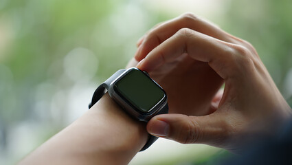 Close up of hands adjusting a modern smartwatch on a wrist outdoors