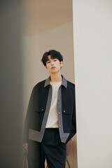 Young man in stylish outfit leaning against a wall.