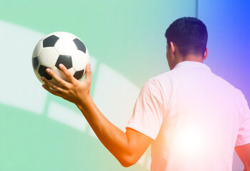 Homem de costas segurando bola de futebol.