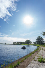 Fototapeta premium Sunny day at a lakeside park with clear blue sky and calm water