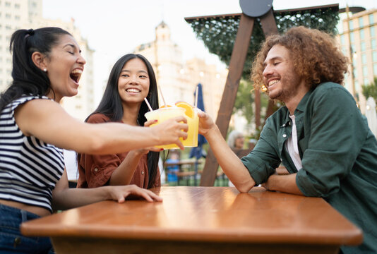 Cheerful multi-ethnic friends toasting with refreshing drinks at a bar, enjoying their time together - Powered by Adobe