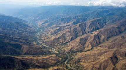 Majestic Aerial View of a Winding River Through Mountainous Valley Landscape Under a Hazy Sky