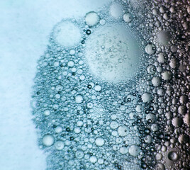 Abstract macro photo of oil bubbles in water with soft blue gradient