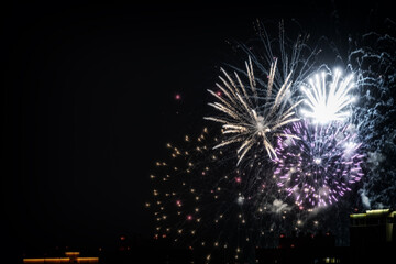 Many fireworks explodes in the black night sky, illuminating the darkness with bursts of color and light