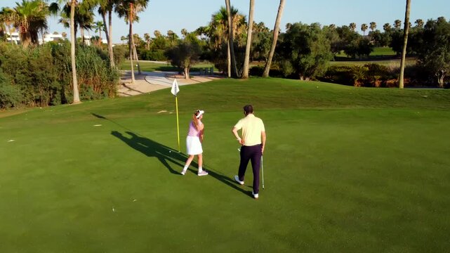 Golf instructor coaching female golfer on putting green - Powered by Adobe