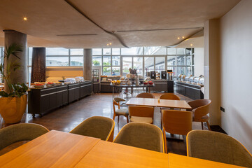 Interior of a hotel restaurant with breakfast served on buffet tables