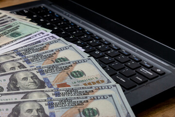 US Dollar Bills on Laptop Keyboard. Various US dollar notes laid on a laptop keyboard, illustrating...