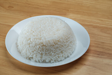 streamed white Thai's jasmine rice in the white clean dish isolated put on the wooden plate dinner table