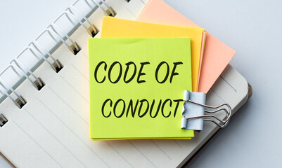 A yellow and orange sticky note with the word Code of Conduct written on it