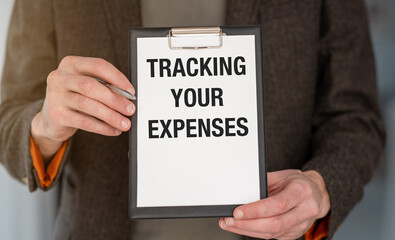 A man holding a clipboard with the words Tracking Your Expenses written on it