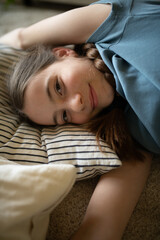 Teenage girl lying on pillow with gentle smile