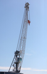 A crane is tall and white with a blue sky in the background