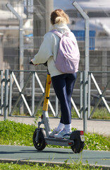 A girl is riding a scooter with a backpack on