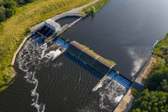 Top-down aerial view of Woolston Weir on the River Mersey in Warrington, a hydroelectric facility harnessing the river&rsquo;s flow, with water cascading over the structure