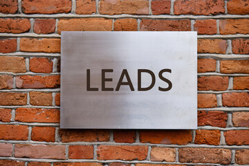 Lead generation, analysis of financial business marketing strategies concept,LEADS written on a smooth metal panel is affixed to an old brick wall