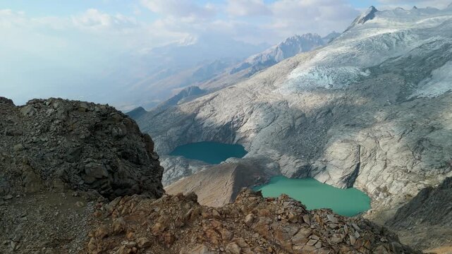 Rocky terrain, glacier slopes, and twin turquoise lakes of Paso del Zorro in the high Andes of Peru - dramatic aerial parallax