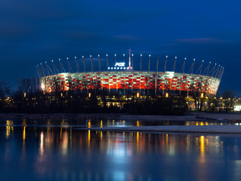 2025-02-01; PGE National Stadium illuminated at night by the Vistula river reflection in Warsaw, Warsaw, Poland