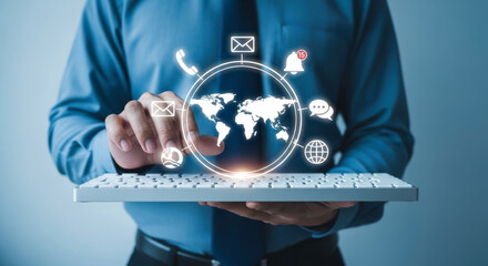 A man holding a keyboard with a world map and communication icons hovering above it in a blue setting