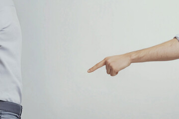 Close up of a male hand pointing an accusatory index finger at another person, a concept of blame, conflict, and singling someone out for responsibility