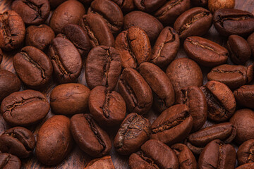 Roasted organic coffee beans background. Close-up view of roasted coffee beans forming a rich brown textured background. Showcasing their natural shape and surface details.