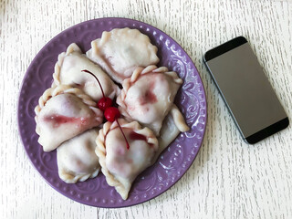 dumplings with cherries and an old telephone on the table nearby. The phone is turned off