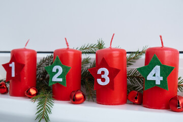 New year and Christmas preparation. Four red advent candles with numbers in white windowsill....