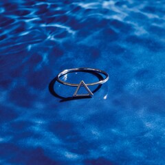 A delicate silver ring featuring a simple geometric triangle design stands elegantly centered.