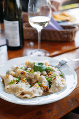 Plate of traditional pierogi garnished with fried onions and herbs served on a wooden table. Polish pierogi, heritage recipes, culinary authenticity, traditional dumplings