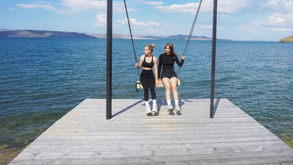 Friends enjoying a carefree moment on a swing overlooking the water
